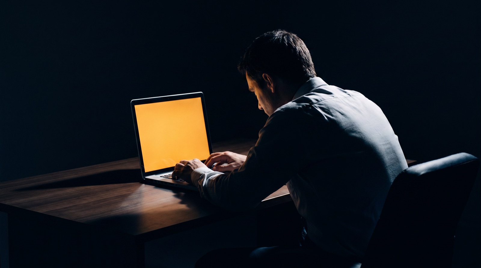 A business owner working alone at a laptop late at night